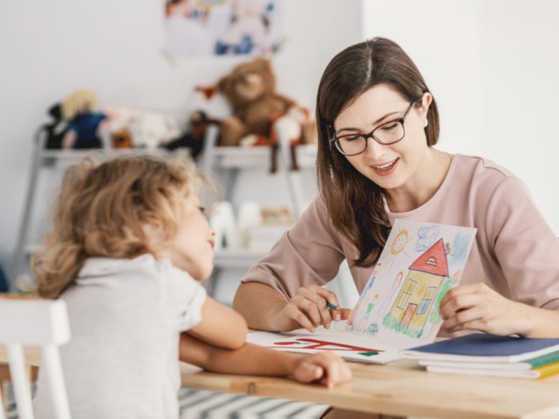 A professional child education therapist having a meeting with a kid in a family support center.